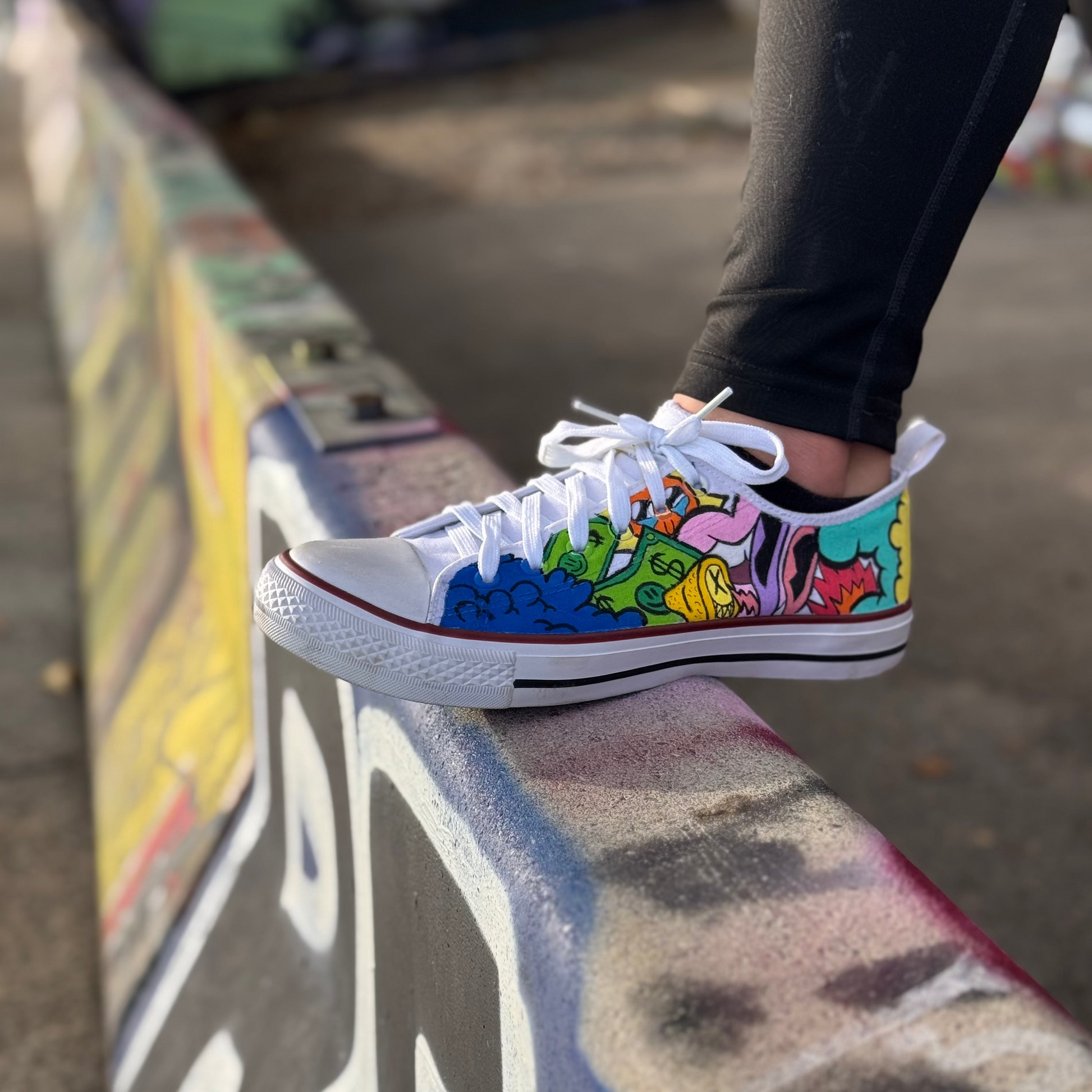 Customized, bold colored doodle art Converse Style low top sneaker, with doodles like clouds, cash, a crying sun, a lemon with a evil face and open lips.